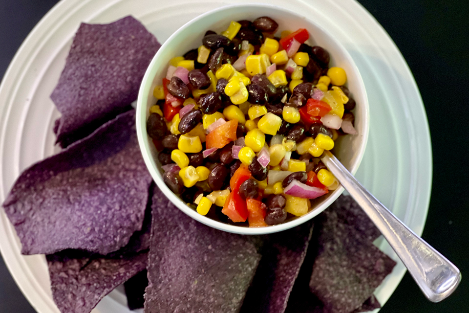 Small bowl of corn and black bean salsa served with a side of blue corn tortilla chips